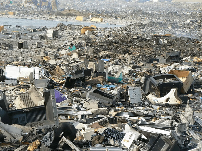 Urban hell scene with scattered electronic waste covering a vast landfill, highlighting severe pollution issues.