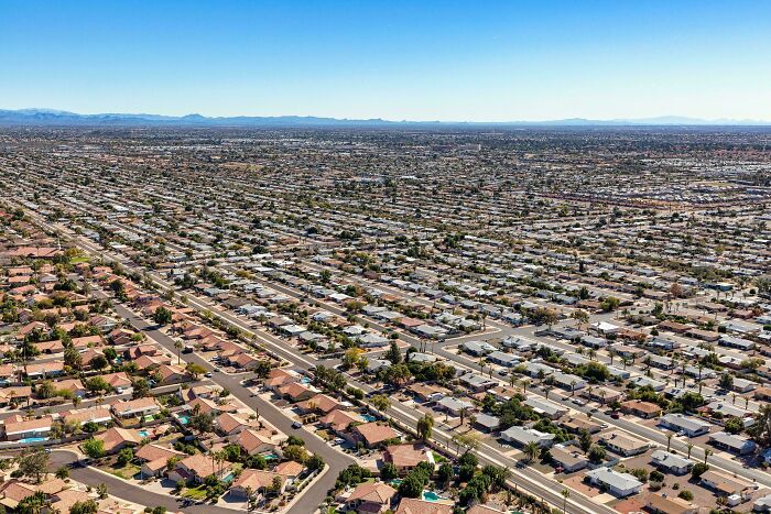 Aerial view of dense urban landscape, showcasing endless rows of houses under a clear sky, epitomizing urban hell.