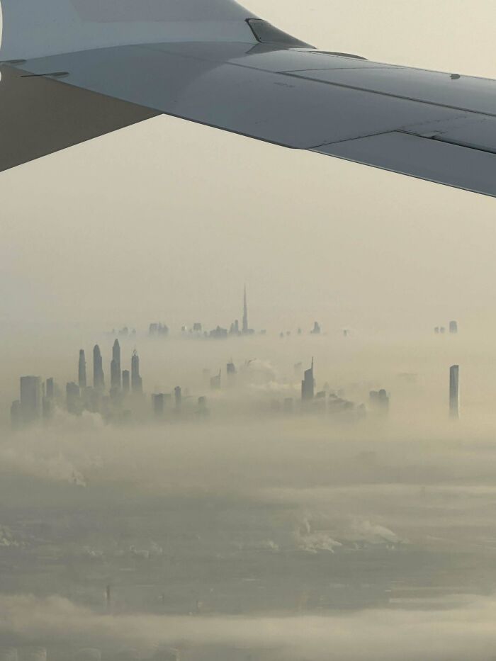 View of a city obscured by fog from an airplane window, illustrating urban hell's surreal appearance.