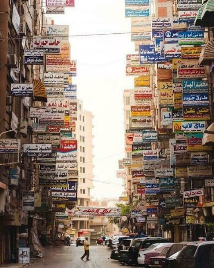 Urban landscape cluttered with numerous signs and advertisements on narrow street.