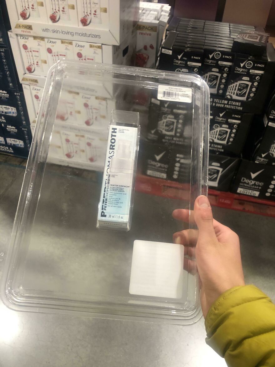 Hand holding oversized plastic package with small item inside, highlighting wasteful unnecessary packaging.