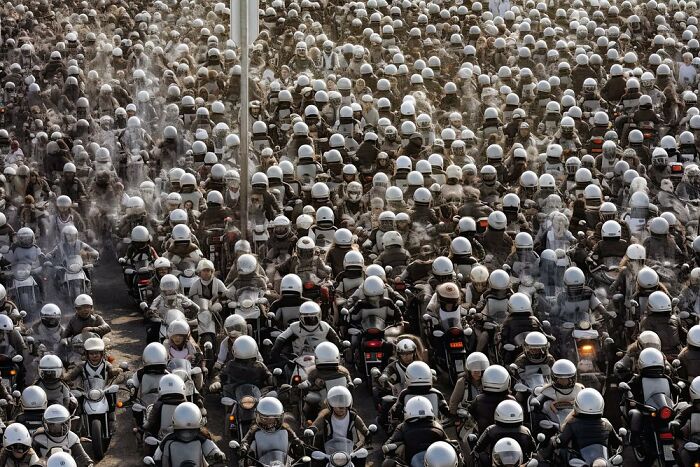 A crowd of motorcyclists wearing helmets, illustrating the symphonic chaos of modernity.