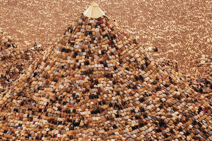 Aerial view of a large crowd forming a pyramid shape, representing Alkan Avcıoğlu's symphonic chaos of modernity.