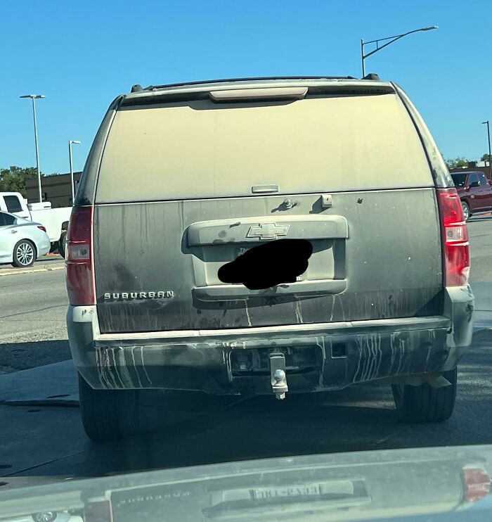 Dusty SUV with license plate covered, parked in a cluttered manner, illustrating the keywords "Idiots-In-Cars."