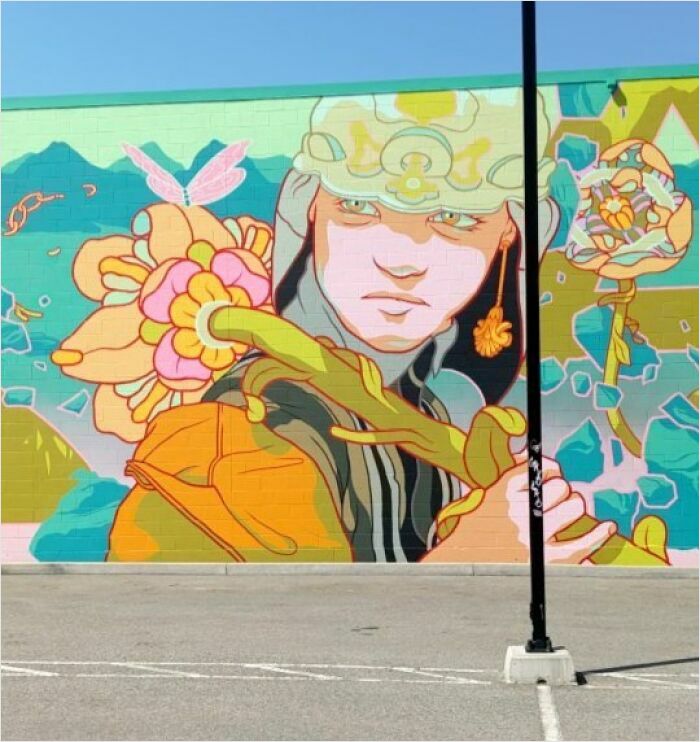 Epic mural by Montréal artist featuring a vibrant character surrounded by flowers on a wall.