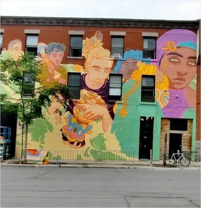 Montréal artist's vibrant mural transforms a brick wall into a stunning street art scene with colorful figures.