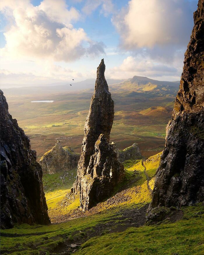 Majestic rock formation in a lush green valley under a cloudy sky, showcasing incredible world photos.