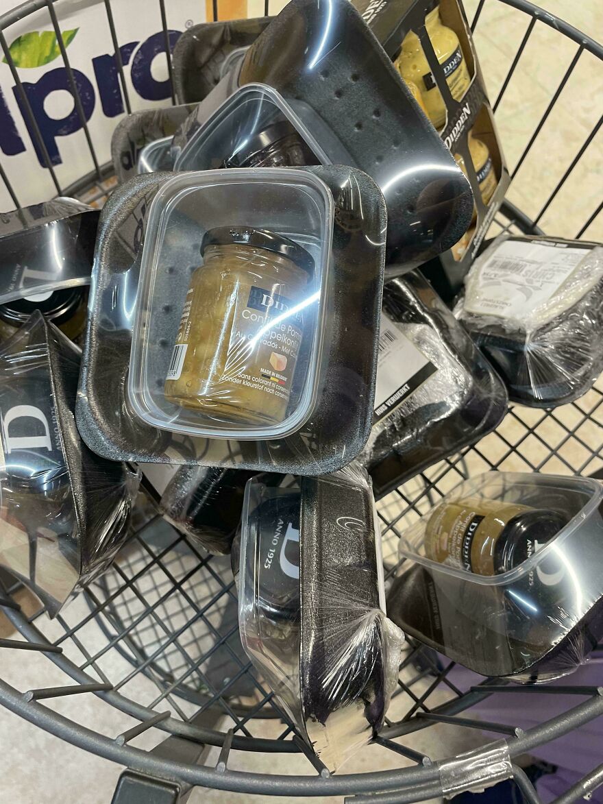 Jars with wasteful unnecessary packaging in a wire basket at a store.