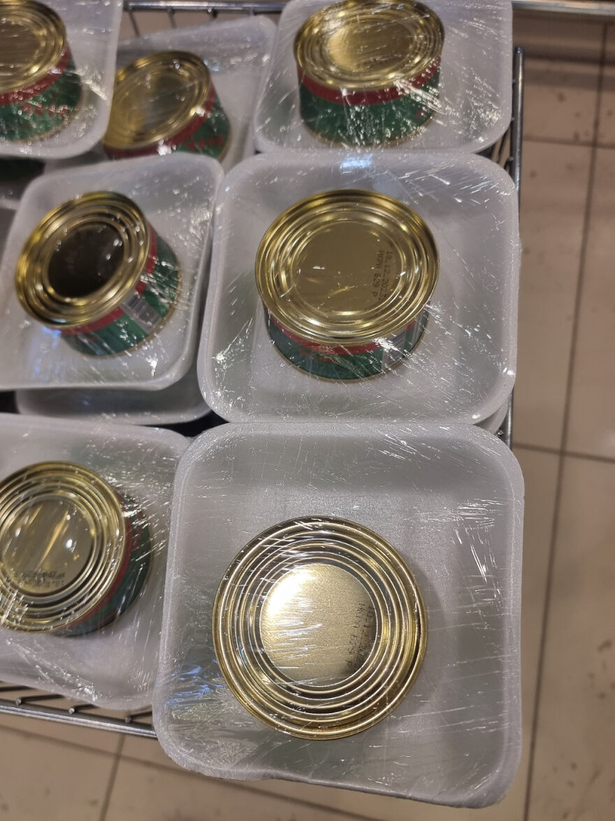 Cans wrapped in excessive plastic, illustrating wasteful unnecessary packaging in a supermarket setting.