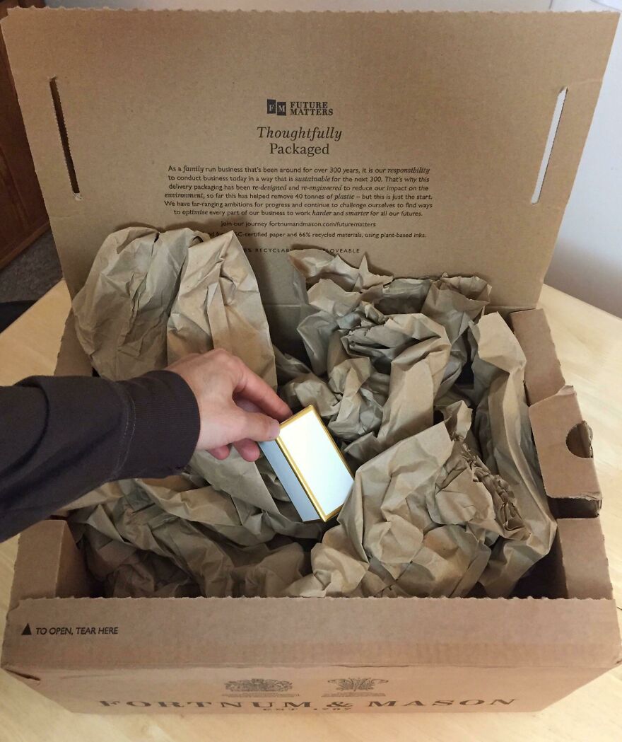 A small item being taken from a large box with excessive paper, highlighting wasteful unnecessary packaging.