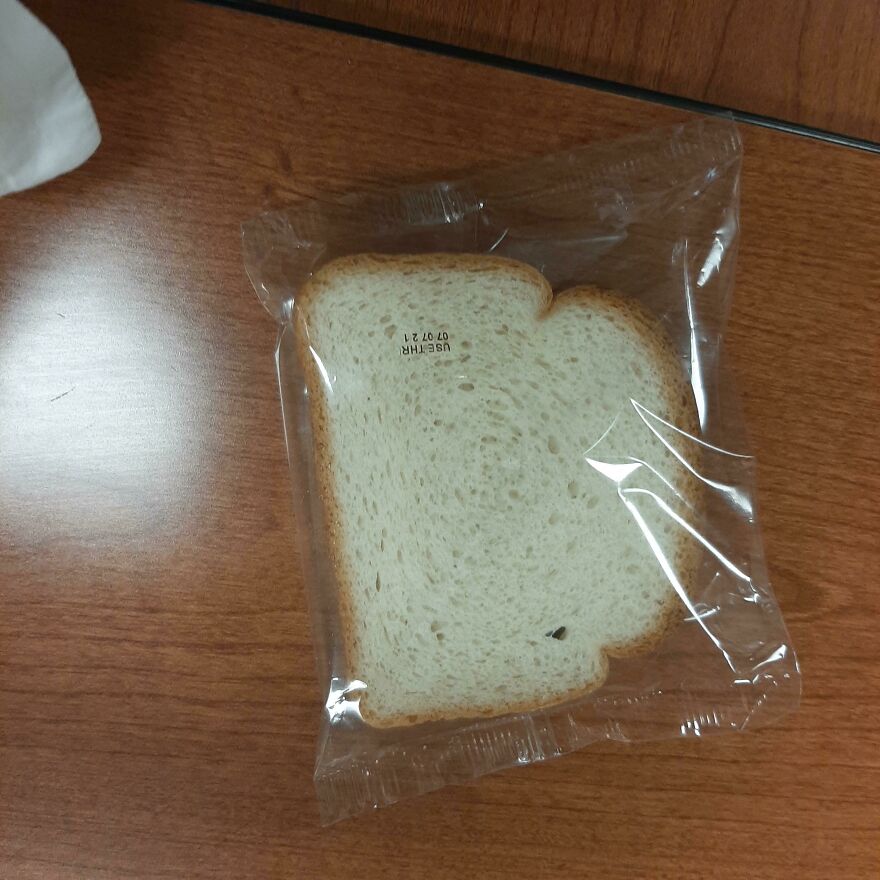 Slice of bread in plastic wrap on a table, demonstrating wasteful unnecessary packaging.