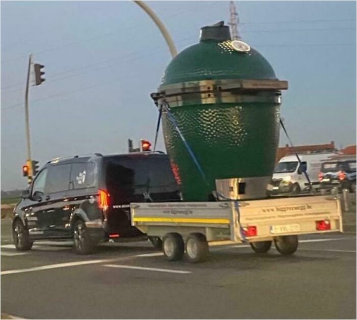 Van towing a massive green ceramic grill on a trailer, showcasing absolute units things.