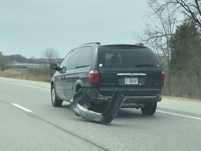 Minivan driving with detached rear bumper dragging on the road, highlighting reckless driving.