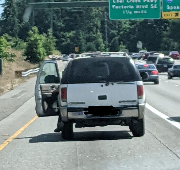 SUV on highway with open driver door, illustrating careless driving behavior.