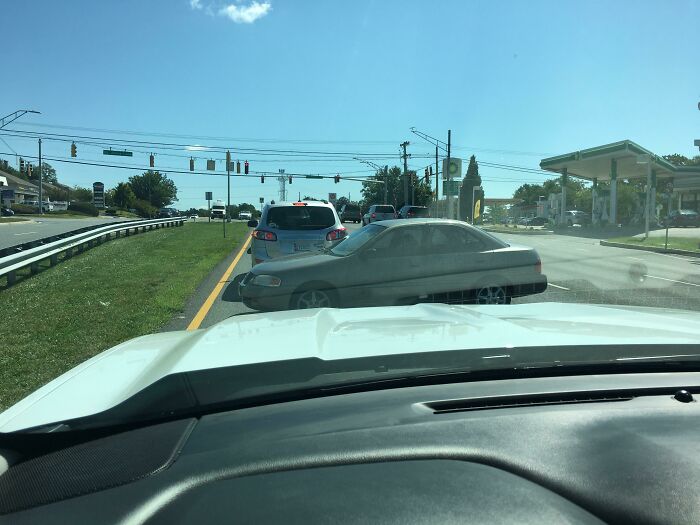 Car dangerously cutting into traffic at an intersection, illustrating careless driving behavior seen in "Idiots-In-Cars" scenarios.