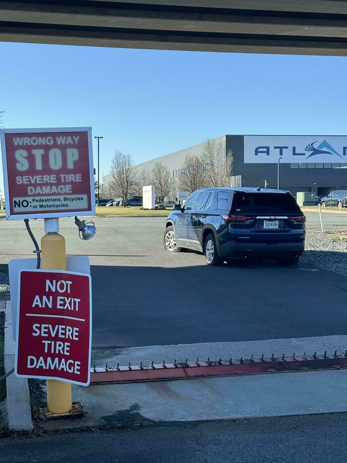 Car parked facing the wrong way near "Not an Exit" sign, potential tire damage, highlighting drivers' mistakes.