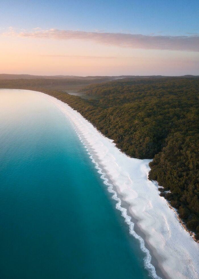 Incredible World Photos: aerial view of a pristine beach with turquoise water and lush green forest.