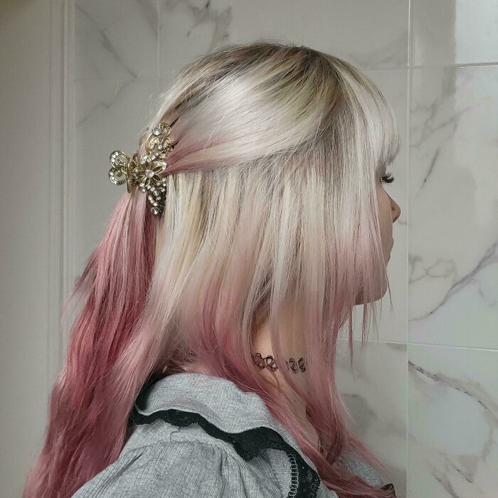 Blonde hair with pink highlights styled using an ornate hair clip, showcasing changing hair color.