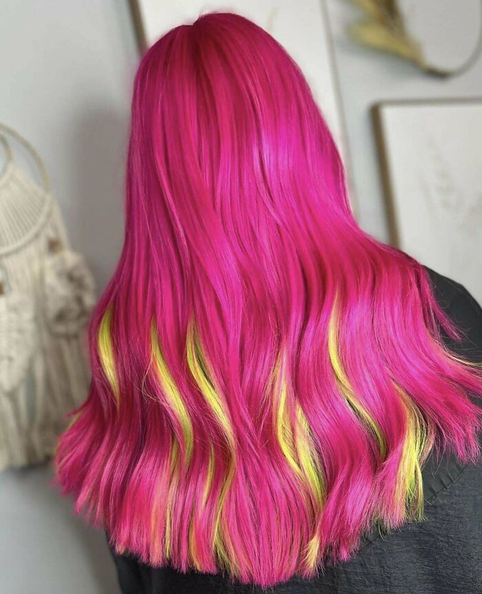 Vibrant pink and yellow hair colors, showcasing changing hair color trends, in a stylish indoor setting.