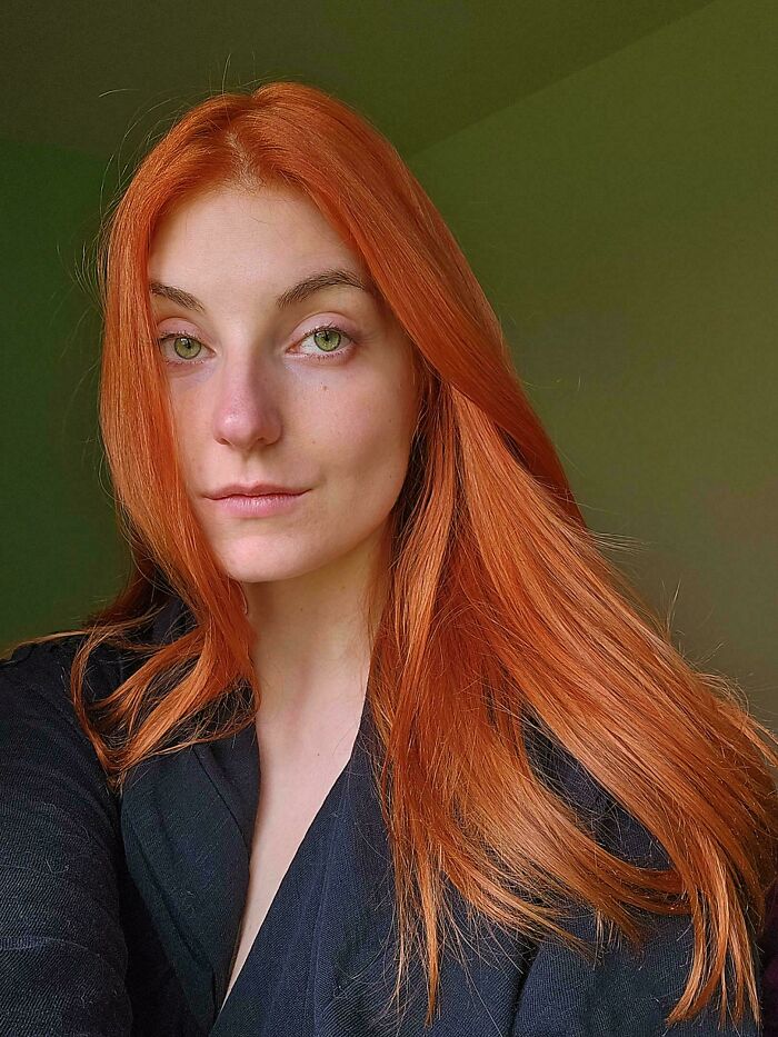 Woman with long, vibrant red hair wearing a black top, capturing the essence of changing hair color.