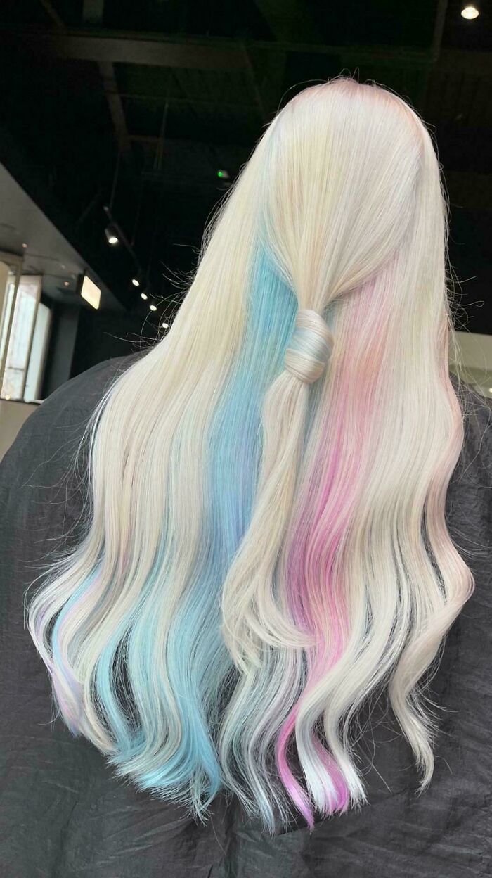 Pastel-changing hair color with shades of pink and blue on long, wavy hair.