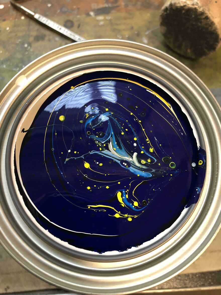 Colorful accidental art pattern in a paint can, featuring swirling blue and yellow designs.