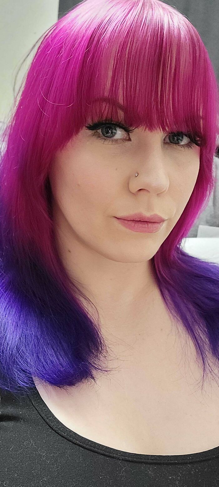 Woman with striking pink and purple hair, showcasing changing hair color.