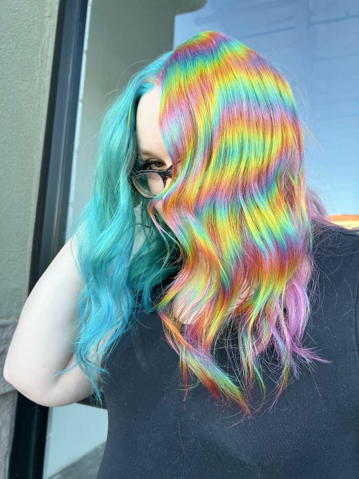 Person with vibrant rainbow and teal hair, showcasing changing hair color artistry.