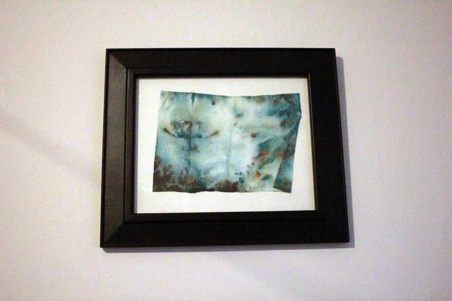 Framed abstract artwork resembling accidental art with blue and brown hues.