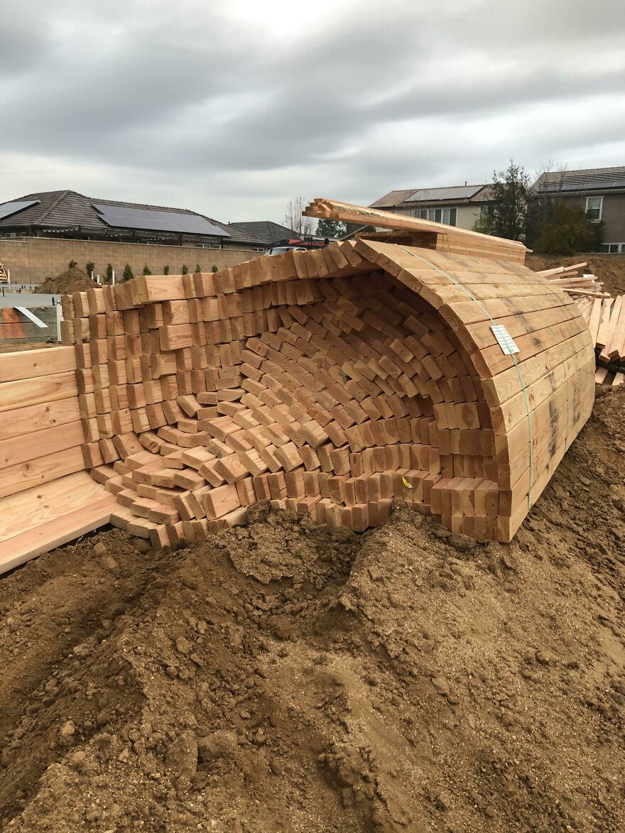 Stack of wood planks inadvertently forming a wave-like structure, an example of accidental art.