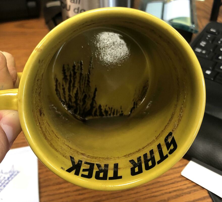 Coffee residue resembling a forest scene inside a yellow Star Trek mug, exemplifying accidental art.