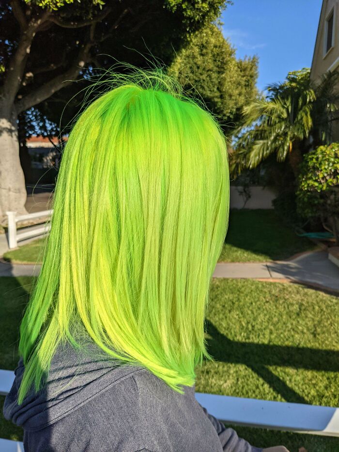 Bright green hair in sunlight, showcasing changing hair color outdoors.