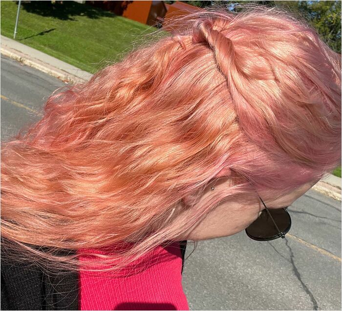 Person with pink, wavy hair and sunglasses outdoors, showcasing a change in hair color.