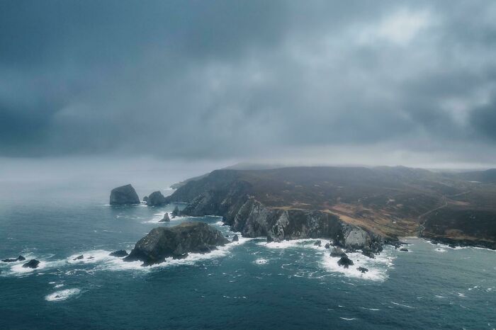 Dramatic coastal cliffs and ocean waves under a stormy sky, showcasing an incredible world photo.