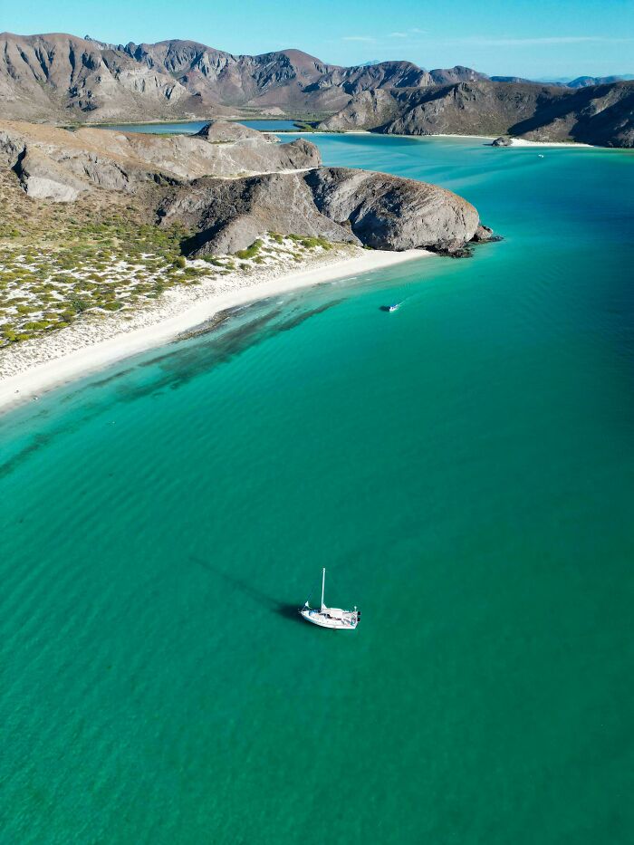 Aerial view of a serene bay with turquoise waters and a sailboat, highlighting the beauty of the incredible world photos.