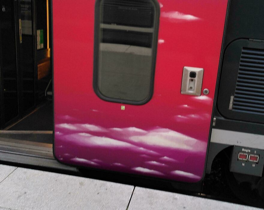 Train door with a sky motif, creating an illusion of looking through clouds.