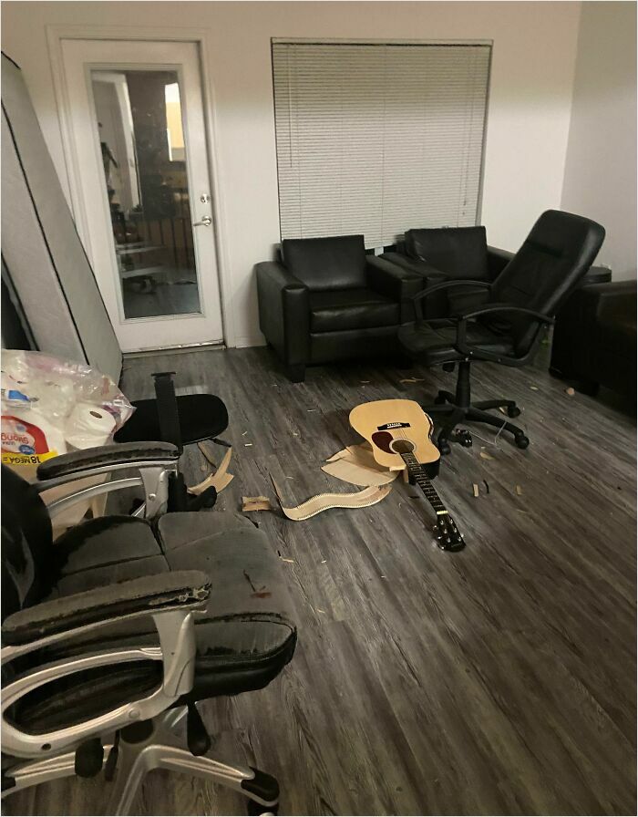 Messy room with broken guitar and damaged chairs, illustrating horrible-roommates scenario.