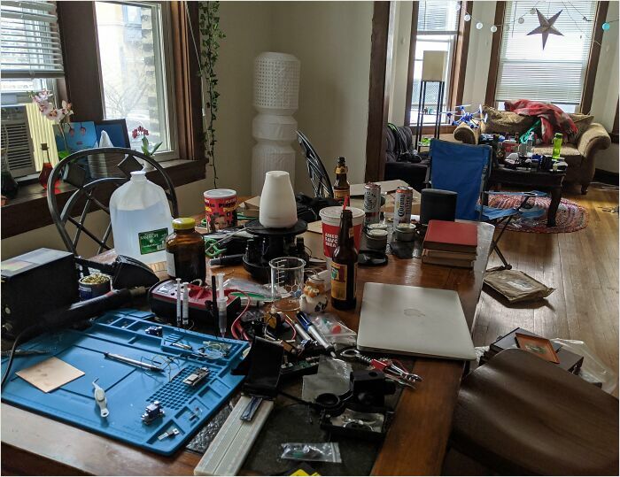 Messy living room with cluttered table, showcasing the typical chaos of horrible roommates.