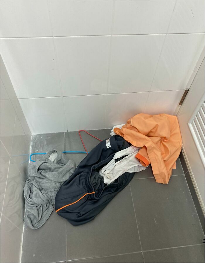 Clothes scattered on a bathroom floor, highlighting horrible roommates' messy habits.