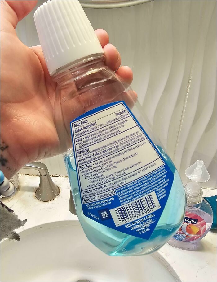 Person holding a toilet bowl cleaner mistaken for mouthwash on a bathroom sink—horrible-roommates scenario.