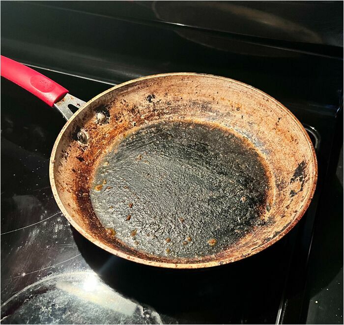 A dirty frying pan with burnt residue, illustrating a typical issue with horrible roommates.