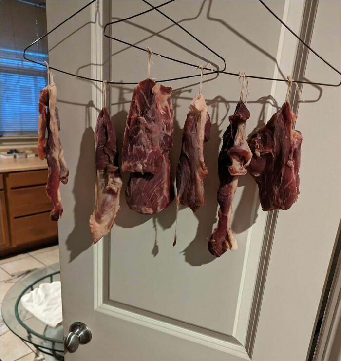 Raw meat hanging on hangers behind a door, representing strange roommate behavior.