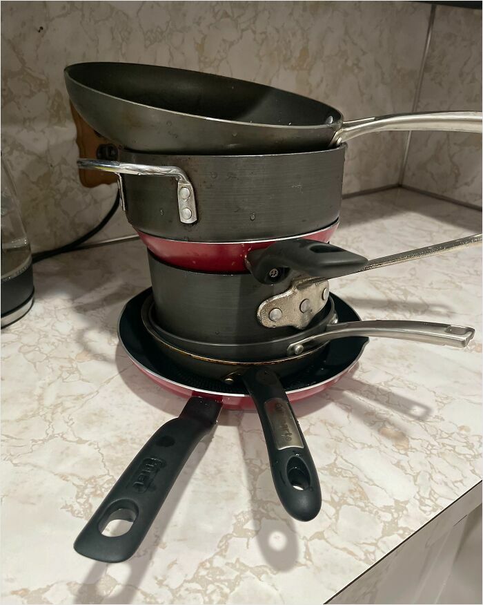 A messy stack of pans and pots on a kitchen counter, illustrating horrible roommates' disorganized habits.