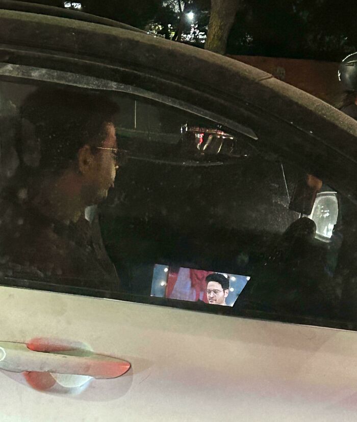 Person in car watching video on phone while driving at night.