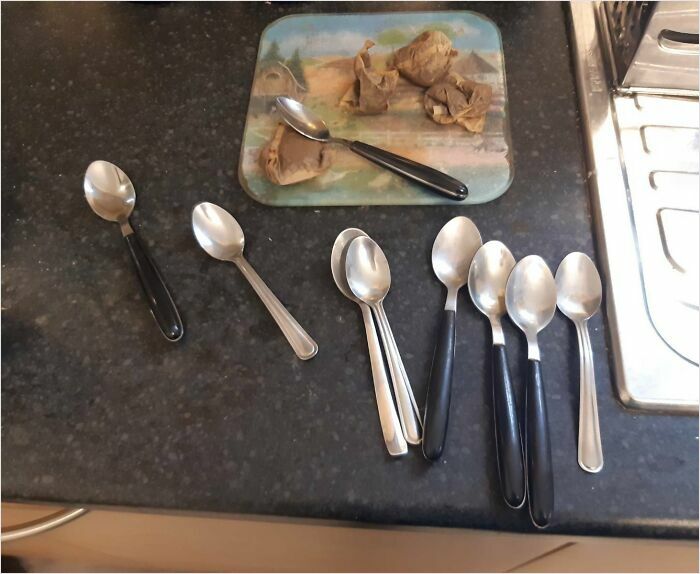 A cluttered kitchen counter with many spoons and used teabags, depicting horrible roommates' mess.