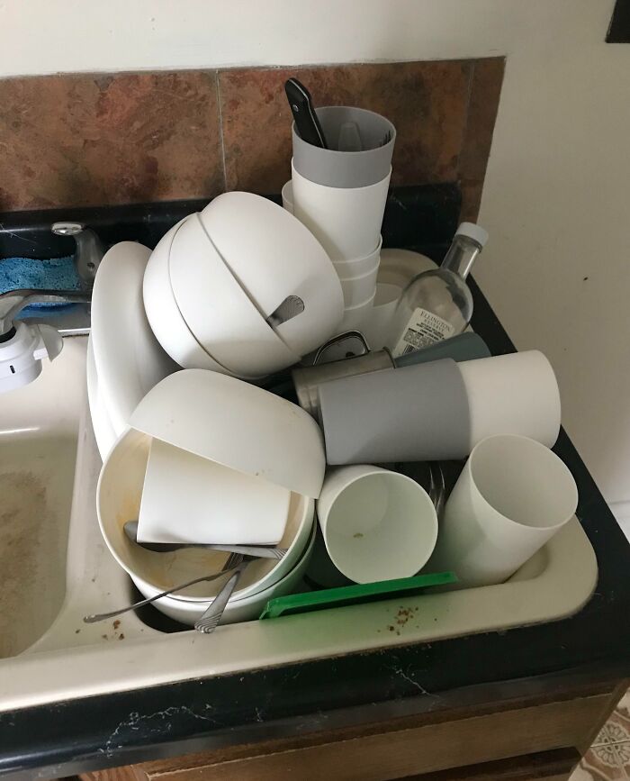 Stacked dirty dishes in a kitchen sink, illustrating a common issue with horrible roommates.