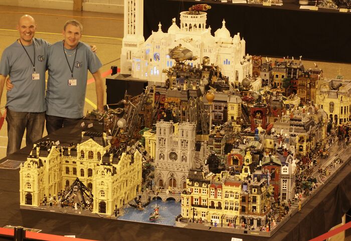 Two people standing beside an intricate cityscape created with cool LEGO builds.