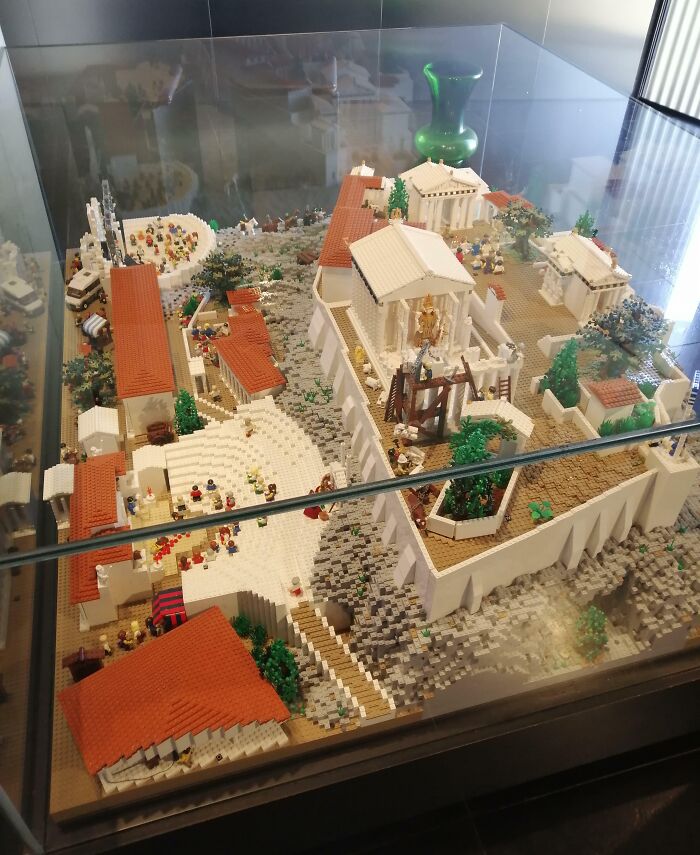 Intricate LEGO build of an ancient cityscape displayed in a glass case.