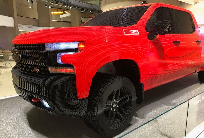 Red pickup truck made entirely of LEGO bricks, showcasing a creative Cool-LEGO-Builds design in an exhibit setting.