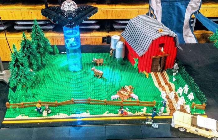 Cool LEGO builds scene with a UFO, a barn, cows, and minifigures on a green baseplate.